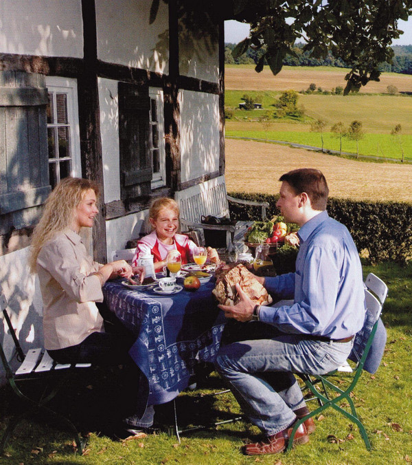 Auch eine Ferienwohnung kann ein Qualitätsgastgeber sein. Eine Familie frühstück gemütlich draußen.