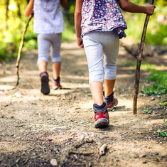 Zwei Kinder wandern durch den Wald auf Schatzsuche.