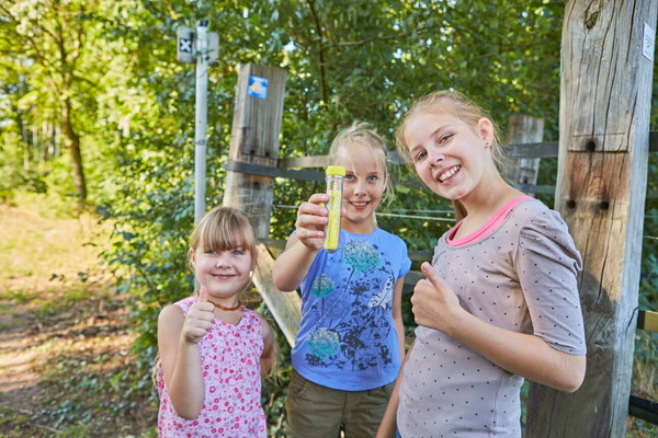 Drei Mädels waren erfolgreich und haben einen Cache gefunden. Sie präsentieren stolz das Röhrchen.